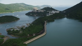 SS01_0065 - 5K stock footage aerial video fly over dam and reservoir to approach harbor-side apartment buildings on Hong Kong Island, China