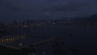 SS01_0121 - 5K stock footage aerial video approach skylines of Kowloon Hong and Kong Island from the port at night, China