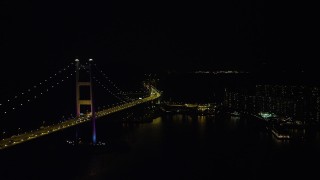 SS01_0245 - 5K stock footage aerial video of flying between the Tsing Ma Bridge and waterfront apartment buildings at night in Hong Kong, China