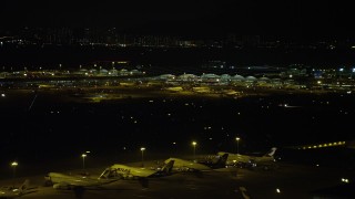 SS01_0280 - 5K stock footage aerial video of Hong Kong International Airport Terminals at night, and tilt to parked airliners, China