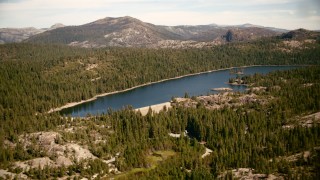 TS01_292 - 1080 stock footage aerial video fly over trees to approach the Lake Valley Reservoir, Sierra Nevada Mountains, California