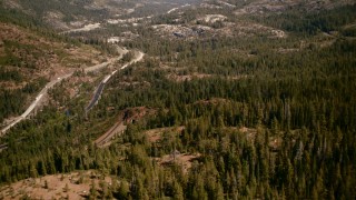 TS01_294 - 1080 stock footage aerial video flyby train tracks, tilt to reveal mountain highway, Sierra Nevada Mountains, California