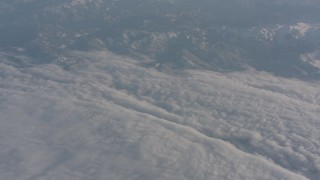 WA002_037 - 4K stock footage aerial video pan across Sierra Nevada Mountains and a dense layer of clouds, California