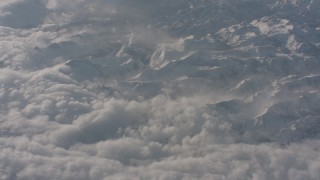 WA002_062 - 4K stock footage aerial video fly away from snowy mountains and tilt to dense clouds below in the Sierra Nevada Mountains, California