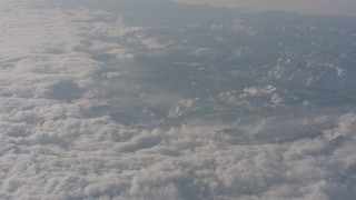 WA002_063 - 4K stock footage aerial video tilt from clouds to reveal snowy mountains while flying away from Sierra Nevada Mountains, California