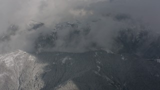 WA004_080 - 4K stock footage aerial video of a bird's eye view of clouds, revealing snowy mountain ridges in Washington