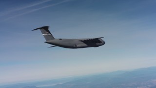 WAAF01_C012_0117G5 - 4K stock footage aerial video tilt to reveal a Lockheed C-5 flying over hills in Northern California