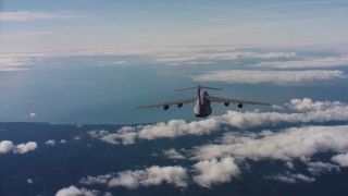 WAAF01_C038_011776 - 4K stock footage aerial video track Lockheed C-5 jet flying over mountains toward Pacific Ocean, Northern California