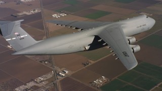 WAAF01_C081_0117PS - 4K stock footage aerial video of a Lockheed C-5 in flight over farms and leaving frame in Northern California