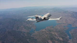 WAAF02_C007_0117AS - 4K stock footage aerial video of revealing a Learjet C-21 flying toward hills and a lake in Northern California