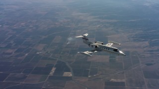 WAAF02_C014_0117MN - 4K stock footage aerial video of a Learjet C-21 as it turns and flies over farmland in Northern California