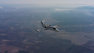 WAAF02_C015_01179B - 4K stock footage aerial video of flying around a Learjet C-21 in the air over farmland of Northern California