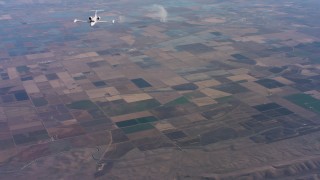 WAAF02_C016_0117AV - 4K stock footage aerial video of a reverse view of a Learjet C-21 over farmland in Northern California