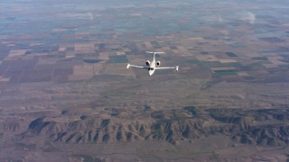 WAAF02_C017_0117TS - 4K stock footage aerial video of reverse view of a Learjet C-21 flying over farm fields in Northern California