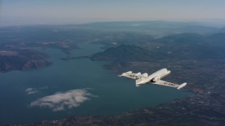 WAAF02_C021_0117PA - 4K stock footage aerial video fly around tail of a Learjet C-21 in flight near lake in Northern California