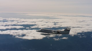 WAAF02_C022_01171S - 4K stock footage aerial video of a Learjet C-21 in flight near cloud-topped mountains in Northern California