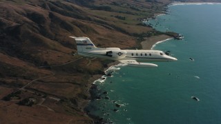 WAAF02_C033_0117PT - 4K stock footage aerial video of a Learjet C-21 flying over the coast toward the ocean in Northern California