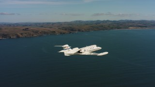WAAF02_C036_0117TJ - 4K stock footage aerial video track a Learjet C-21 flying over the ocean near the coast in Northern California