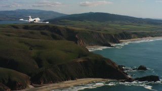 WAAF02_C038_01173P - 4K stock footage aerial video of revealing a Learjet C-21 flying along the coast in Northern California