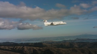 WAAF02_C050_0117QE - 4K aerial stock footage video of a Learjet C-21 over the Marin Hills, California