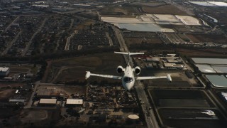 WAAF02_C055_01177K - 4K stock footage aerial video of a reverse view of a Learjet C-21 flying over industrial buildings in Northern California