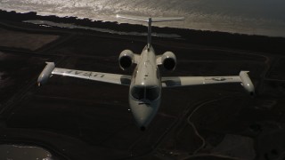 WAAF02_C059_01174D - 4K stock footage aerial video of a reverse view of a Learjet C-21 entering frame and flying over bay, Northern California
