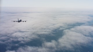 WAAF04_C069_011863_S000 - 4K aerial stock footage video of a Boeing KC-135 flying over low coastal clouds in Northern California
