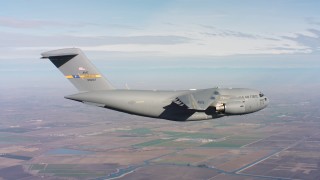 WAAF05_C011_01185N - 4K stock footage aerial video of a Boeing C-17 flying over farm fields in Northern California