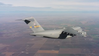 WAAF05_C015_01189N - 4K stock footage aerial video of a Boeing C-17 flying above farmland in Northern California