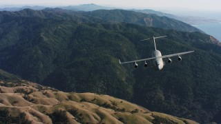 WAAF05_C035_0118SM - 4K stock footage aerial video of a reverse view of a Boeing C-17 over mountains in Northern California