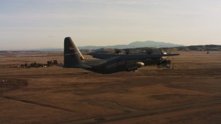 WAAF06_C002_0119TW - 4K stock footage aerial video of a Lockheed Martin C-130J lifting off from Travis Air Force Base at sunset, California