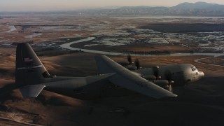 WAAF06_C003_01192T - 4K stock footage aerial video of a Lockheed Martin C-130J flying near marshland at sunset in Northern California