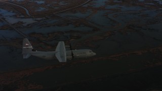 WAAF06_C006_0119G1 - 4K stock footage aerial video of a Lockheed Martin C-130J flying over wetlands at twilight in Northern California