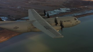WAAF06_C007_0119WJ - 4K stock footage aerial video of revealing a Lockheed Martin C-130J flying over wetlands in Northern California, sunset