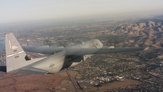 WAAF06_C008_0119Q1 - 4K stock footage aerial video of a Lockheed Martin C-130J over residential neighborhoods at sunset in Northern California