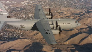 WAAF06_C010_0119DW - 4K stock footage aerial video of a Lockheed Martin C-130J flying near neighborhoods at sunset in Northern California