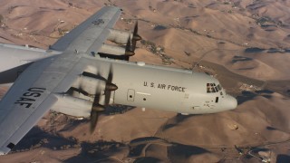WAAF06_C013_0119HX - 4K stock footage aerial video of a Lockheed Martin C-130J in flight over brown hills at sunset, Northern California