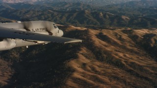 WAAF06_C028_0119QR - 4K stock footage aerial video of revealing a Lockheed Martin C-130J flying over mountains at sunset in Northern California