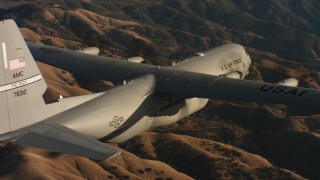 WAAF06_C029_0119C1 - 4K stock footage aerial video of a Lockheed Martin C-130J flying over rolling hills at sunset in Northern California