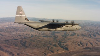 WAAF06_C033_0119HP - 4K stock footage aerial video of a Lockheed Martin C-130J flying high over hills at sunset in Northern California