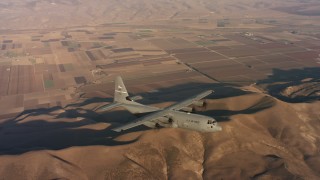 WAAF06_C036_0119QH - 4K stock footage aerial video of a Lockheed Martin C-130J flying over hills and farms at sunset in Northern California