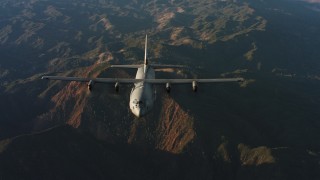 WAAF06_C041_0119KA - 4K stock footage aerial video of a reverse view of a Lockheed Martin C-130J over mountains at sunset in Northern California