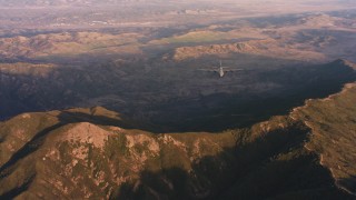 WAAF06_C051_0119NW - 4K stock footage aerial video of a reverse view of Lockheed Martin C-130J over mountains at sunset in Northern California