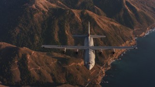 WAAF06_C052_0119WK - 4K stock footage aerial video reverse view of a Lockheed Martin C-130J flying over mountains near coast of Northern California
