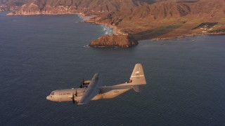 WAAF06_C057_0119EM - 4K stock footage aerial video of a Lockheed Martin C-130J flying near the coast of Northern California at sunset