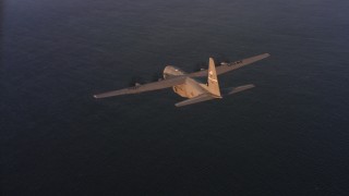 WAAF06_C061_0119SS - 4K stock footage aerial video fly around a Lockheed Martin C-130J over the ocean at sunset in Northern California