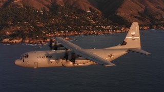 WAAF06_C062_0119BD - 4K stock footage aerial video of a Lockheed Martin C-130J in flight over the ocean near the coast at sunset, Northern California