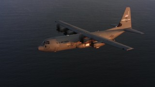 WAAF06_C067_011987 - 4K stock footage aerial video of a Lockheed Martin C-130J flying over the ocean at sunset, Northern California