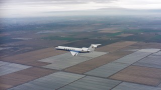 WAAF08_C056_0120GH - 4K stock footage aerial video of a Gulfstream C-37A flying over covered fields in Northern California